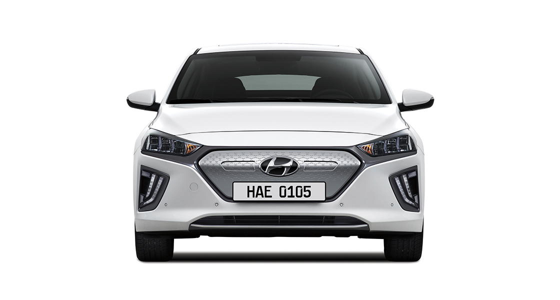 Side view of white Ioniq electric and woman standing in front
