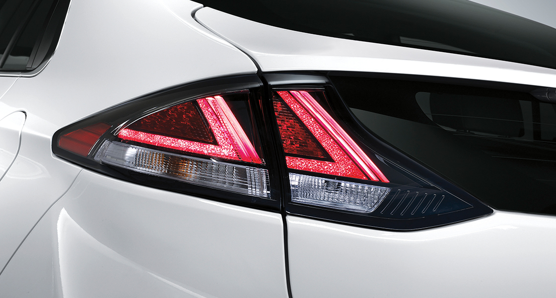 Side view of white Ioniq electric and woman standing in front
