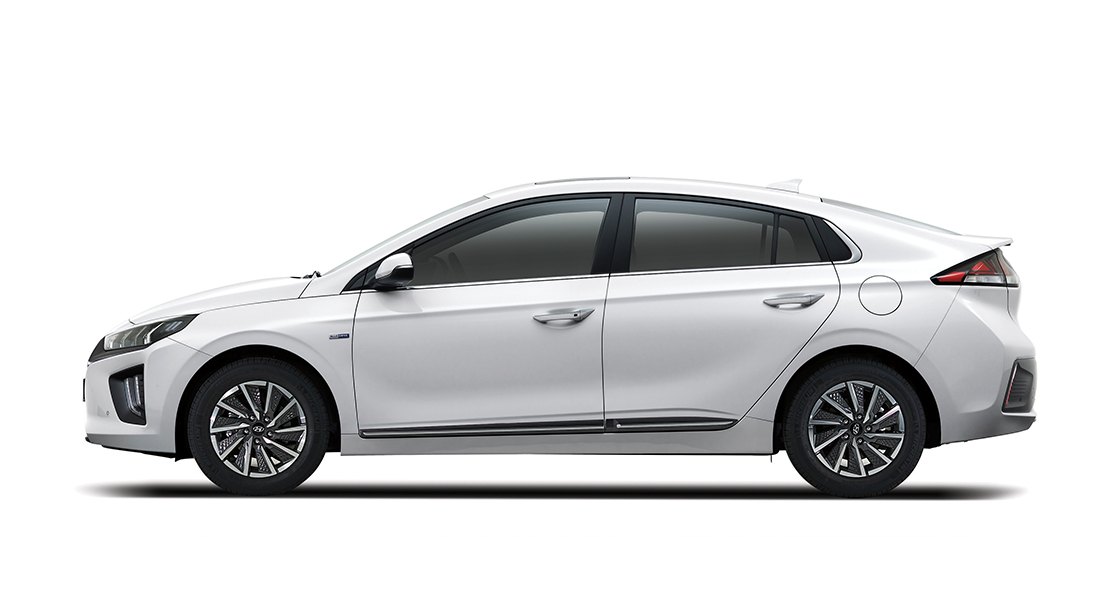 Side view of white Ioniq electric and woman standing in front